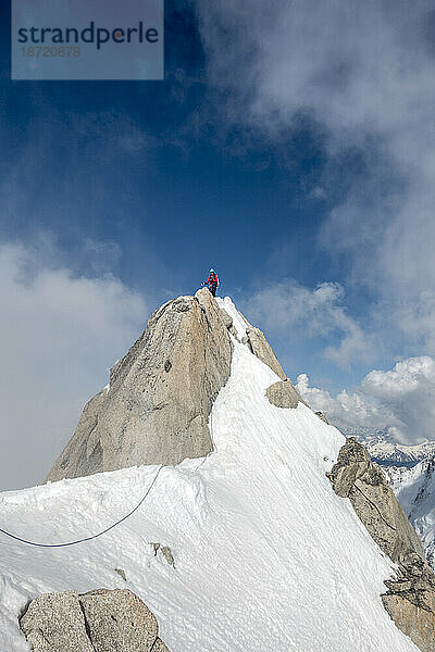 Ein Alpinist im roten Hemd auf dem Gipfel der Aiguille du Chardonnet