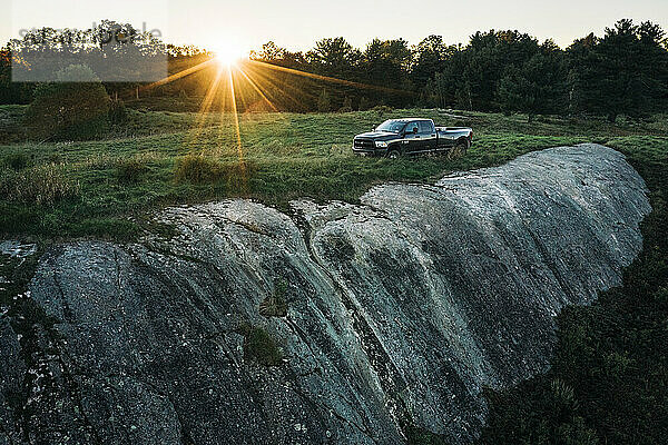 Pickup-Truck auf Felsen bei Sonnenuntergang im Feld