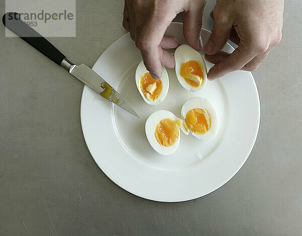 Hartgekochte Eier werden in zwei Hälften geteilt  sodass in der Mitte ein Eigelb zum Vorschein kommt.