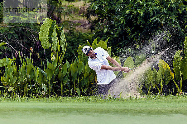 Vorderansicht eines Golfspielers  der einen Rasenfleck in die Luft sprüht