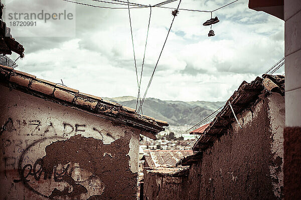 Schuhe hängen an Drähten über einer alten  verfallenen Straße in Peru