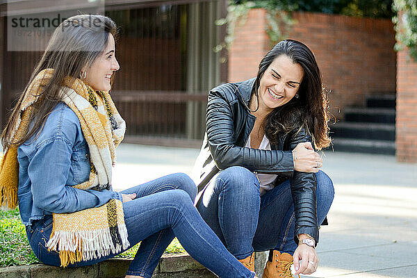 Fröhliche Freunde reden  während sie auf der Straße sitzen