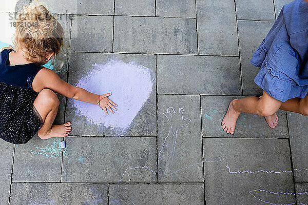 Kind zeichnet mit Kreide auf Beton