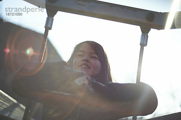 Porträt eines jungen asiatischen Mädchens  das in der Schule in einem Klettergerüst klettert