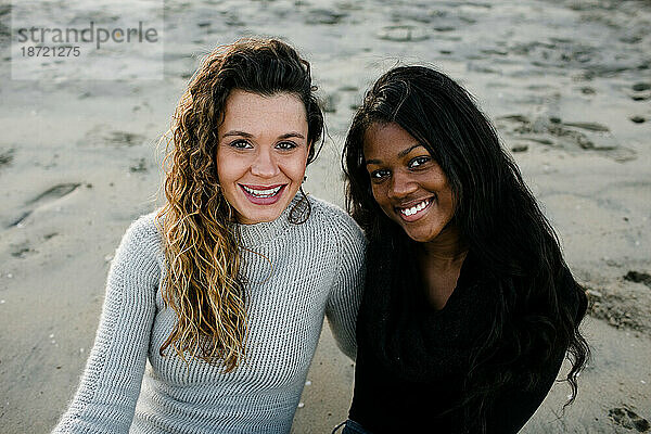 Step mom and step daughter smiling at camera on beach at sunset