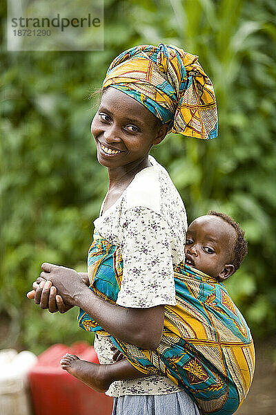 Eine ruandische Frau trägt ihr Kind auf dem Rücken.