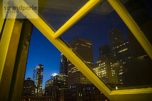 Wolkenkratzer der Innenstadt von Seattle  Washington in der Dämmerung  gesehen durch das Fenster eines Lofts im Pioneer Square-Viertel.