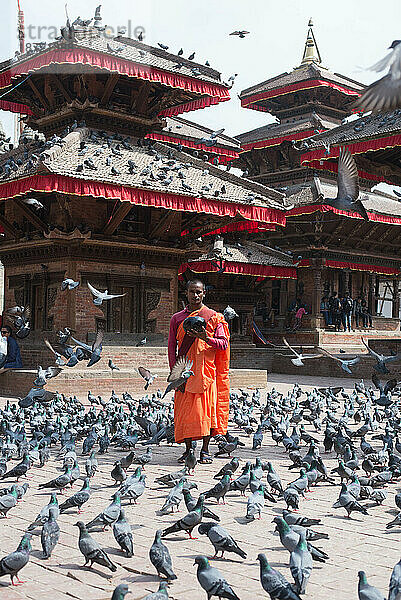 Junger religiöser Mönch steht umgeben von Vögeln mit Opfergaben