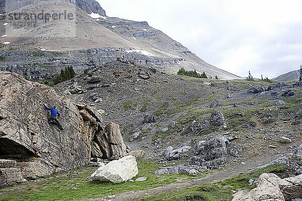Ein Mann klettert auf einen Felsbrocken im Banff NP