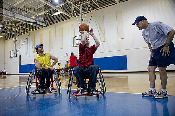 Ein Trainer demonstriert beim Rollstuhlbasketballtraining den Ballhandling im Rollstuhl.