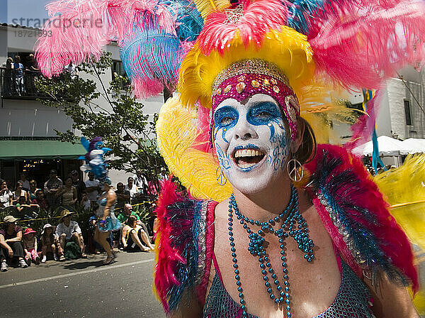 Das bunt bemalte Gesicht einer Frau bei einer Parade in Santa Barbara. Die Parade umfasst extravagante Festwagen und Kostüme.