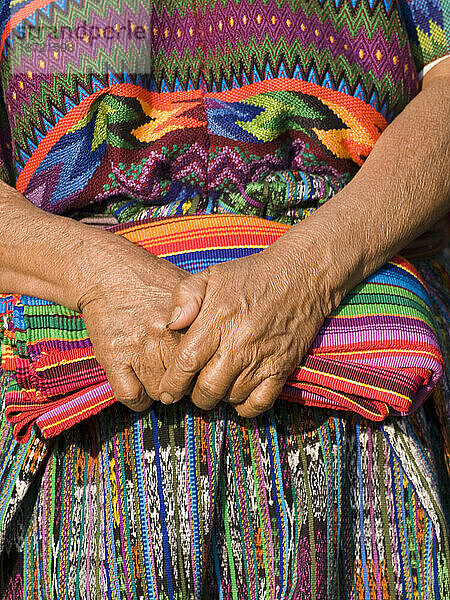 Die Hände einer indigenen guatemaltekischen Frau  die traditionelle Stoffe hält.