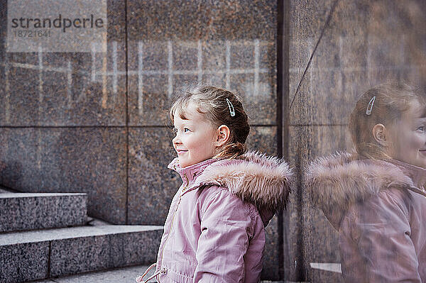 Lächelndes Mädchen in warmer Jacke an der Marmortreppe