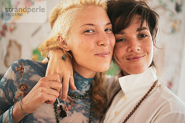 Freches Porträt eines hübschen lesbischen Paares  das zu Hause zusammen lächelt