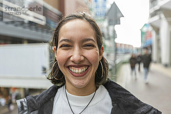 Mixed race woman with wide smile standing on street in city.