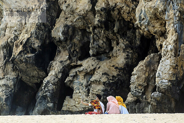 Drei Menschen sitzen am Strand vor Berg  Banda Aceh  Sumatra  Indonesien