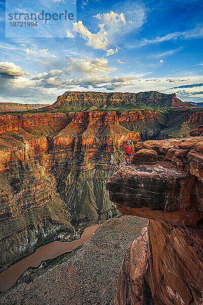 Frau steht auf einer Klippe und blickt auf den Grand Canyon