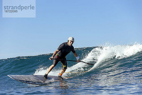 Paddelsurfer reitet auf Welle