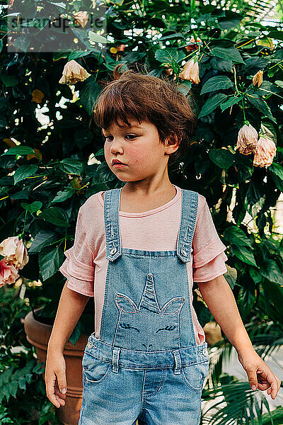Kleines Mädchen steht neben einer Blumenpflanze