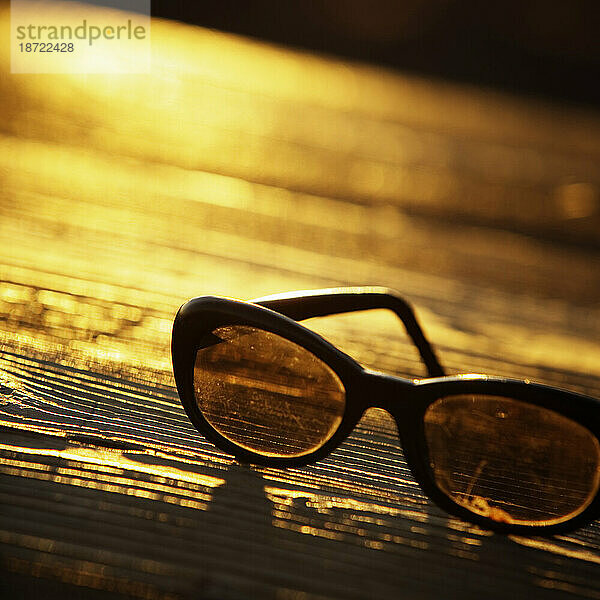 Nahaufnahme einer Sonnenbrille im Freien auf einem Holztisch.