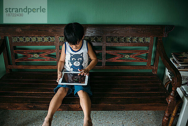 Asiatischer Junge spielt Spiele auf einem Smart-Tablet