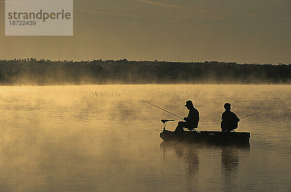 Ein Paar angelt im Morgengrauen Barsch  während im Süden von Illinois Nebel aus dem Wasser aufsteigt.