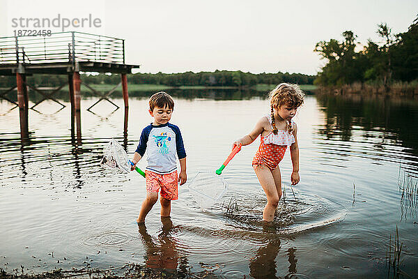 Junge und Mädchen schwimmen und fangen Fische im See