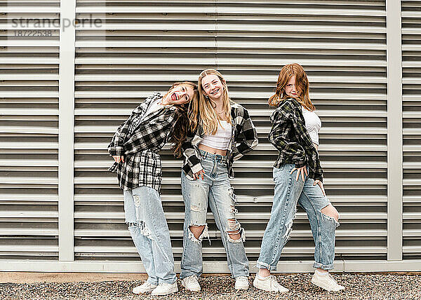 Drei glückliche Teenager-Mädchen posieren vor starken vertikalen Linien.
