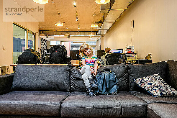 Porträt eines kleinen Mädchens  das auf der Couch im Büro sitzt