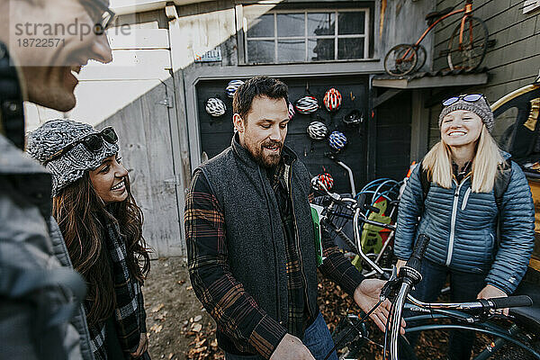 Eine Gruppe junger Freunde lacht  während sie sich Fahrräder zum Mieten ansieht.