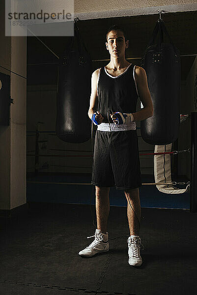 Junger Boxer steht mit Springseil  um im Fitnessstudio mit dem Training zu beginnen.