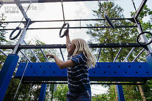 Mädchen schwingt auf Ringen auf dem Spielplatz