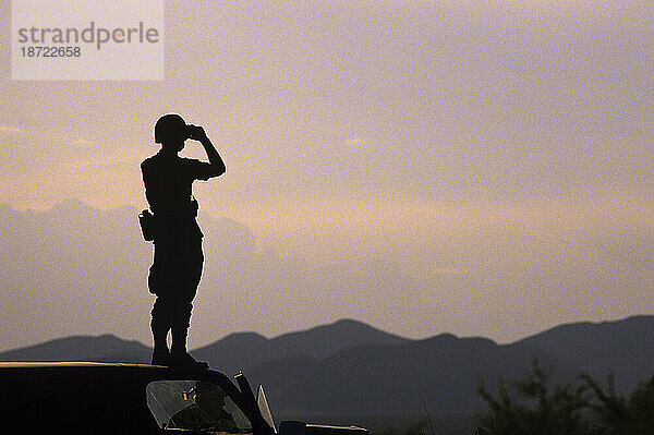 Soldat steht auf dem Dach eines Lastwagens und betrachtet die Umgebung mit einem Fernglas während einer Übung in Ft. Glückseligkeit  El Paso  TX.