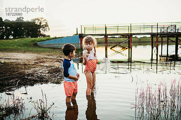 Junges Mädchen zeigt einem kleinen Jungen einen Fisch  der mit einem Netz im See gefangen wurde