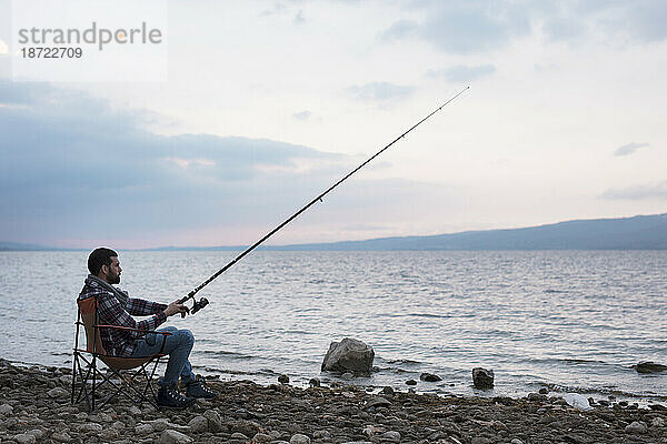 Mann im Lager in der Nähe des Sees  versucht zu angeln