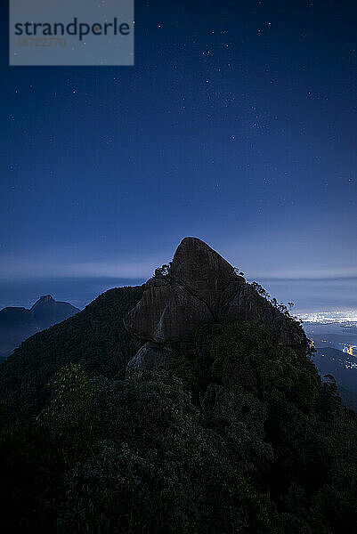 Blick auf den felsigen Berggipfel bei Nacht im Wald unter den Sternen