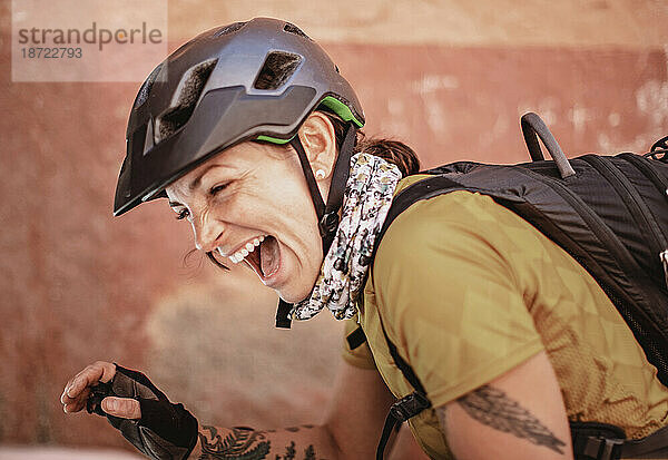 Eine Radfahrerin mit Helm lacht und lächelt vor Freude