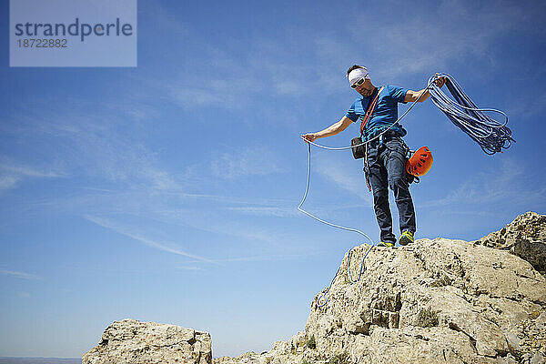 Bergsteiger hebt das Seil auf dem Gipfel des Palomera Peak auf.