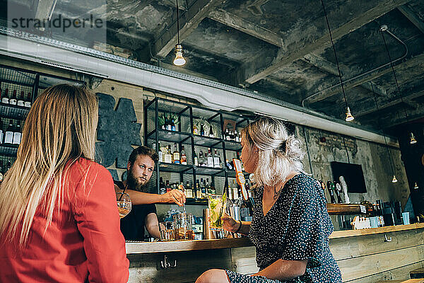 Zwei Freundinnen und Barmann in einer Cocktailbar.