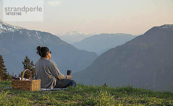 Rückansicht von Frauen  die bei Sonnenuntergang ein Picknick in den Bergen genießen.