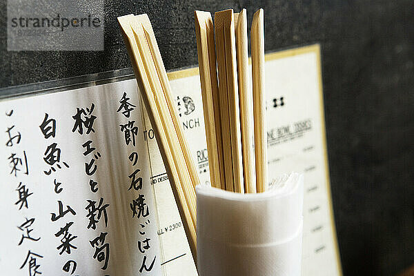 Speisekarte im Restaurant  Essstäbchen im Glas mit Servietten an der Wand  Tokio  Japan.