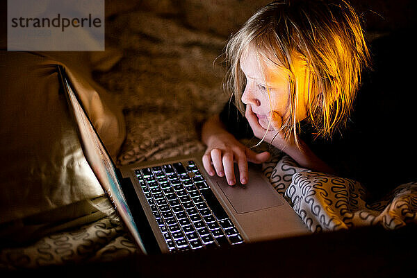 Kind benutzt Laptop im Bett