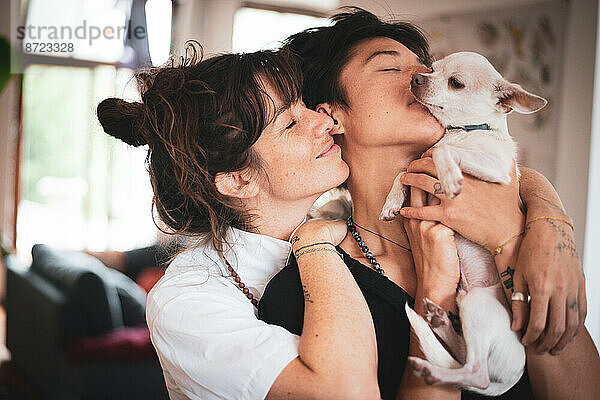 liebevolles Porträt eines queeren interrassischen Familienpaares mit Hund
