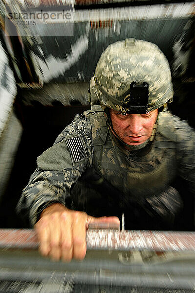 Ein Soldat demonstriert  dass Körperschutz leicht und wendig sein kann  indem er die Leiter eines Gebäudes hinaufsteigt.