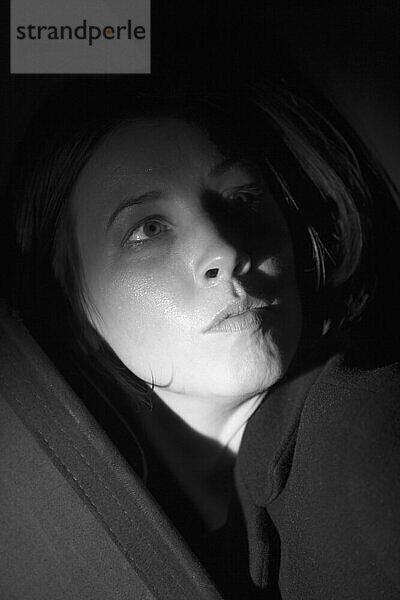 Porträt einer jungen Frau mit Kapuze im Dunkeln.