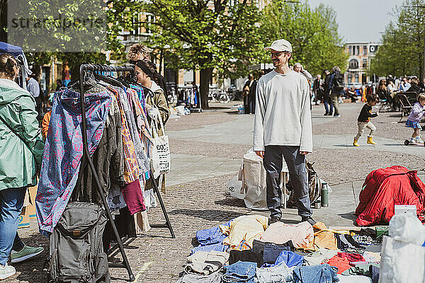 Mann lächelt in der Frühlingssonne und verkauft Second-Hand-Kleidung auf dem Markt