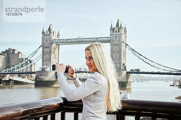 Attraktive Frau  die ein Foto von der Tower Bridge macht