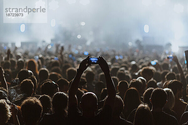 Menschen nehmen mit ihren Mobiltelefonen ein Rockkonzert auf