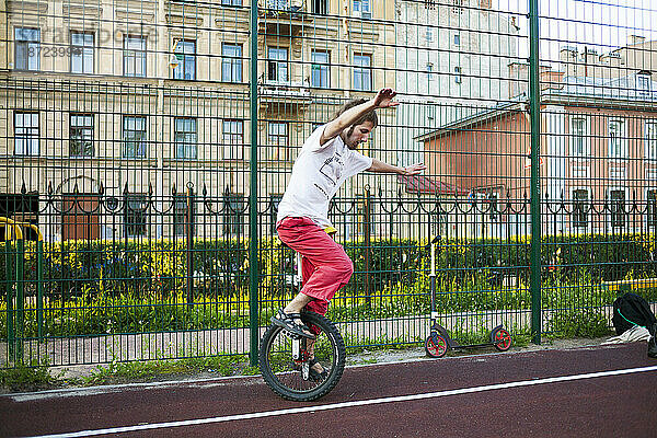 Ein junger Mann balanciert auf einem Einrad im Stadtpark