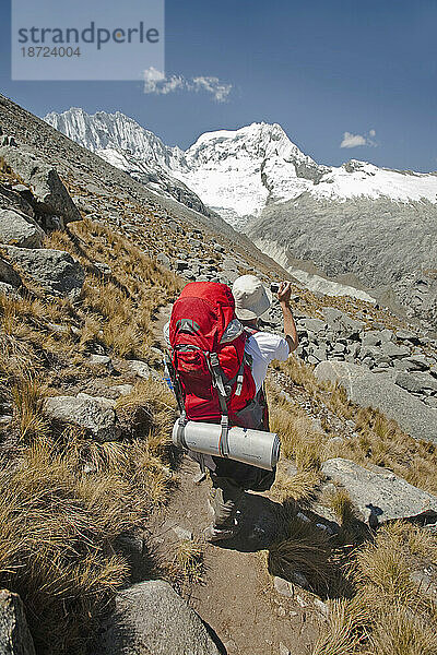 Eine Person macht beim Trekking zum Vallunaraju-Basislager ein Foto von einem verschneiten Gipfel. Huaraz  Peru.